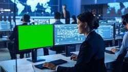 Analyst Monitors Data on Dual Screens in Futuristic Command Center.