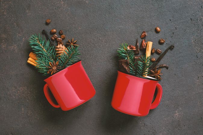Two red ceramic mug with festive filling of pine, coffee beans and anise