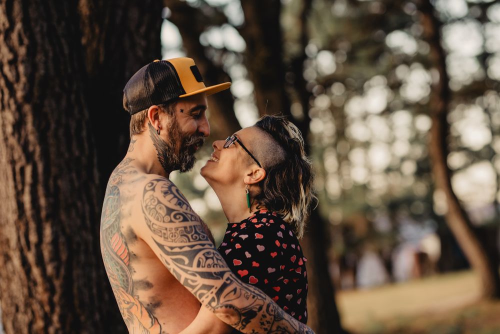 Happy couple hugging near tree in park