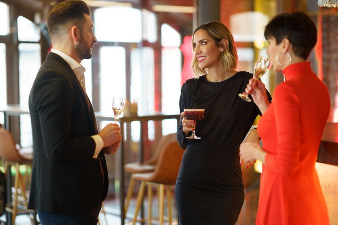 Well dressed friends in a bar with sparkling wine and cocktails