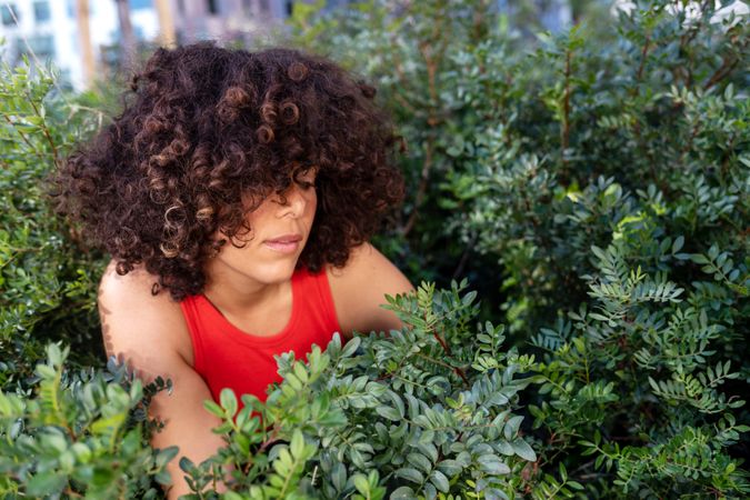 Young woman in red vest surrounded by flowers