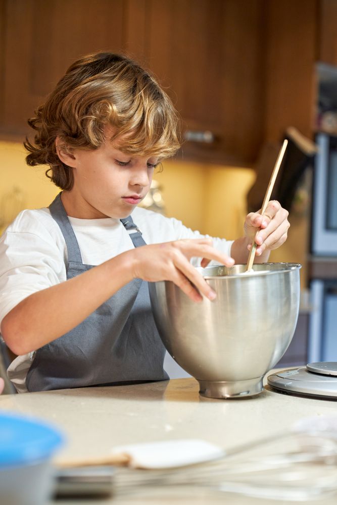 Vertical photo of a child mixing ingredients in a metal container