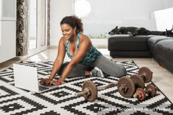 Woman using laptop to do her workout at home 4mkNX0