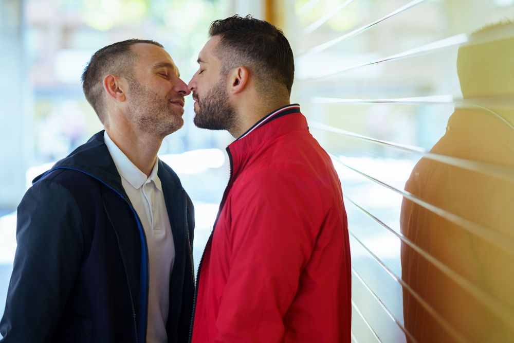 Gay couple kissing on the street with eyes closed