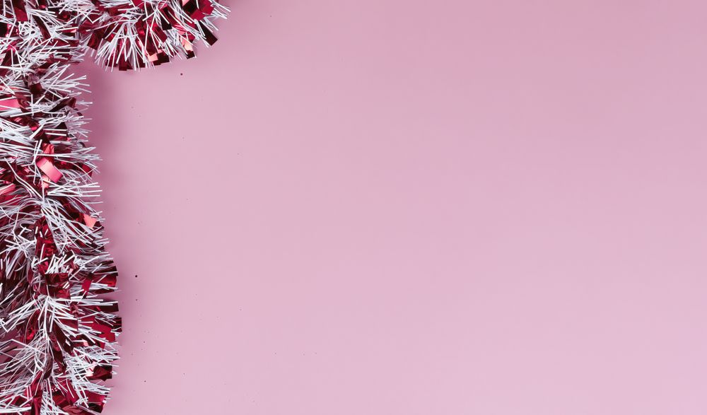 Overhead view of with red and tinsel on a light pink setting for a Merry Christmas or Happy New Year background
