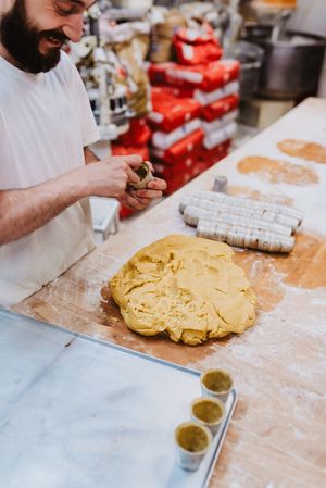 Bearded confectioner putting dough into cup