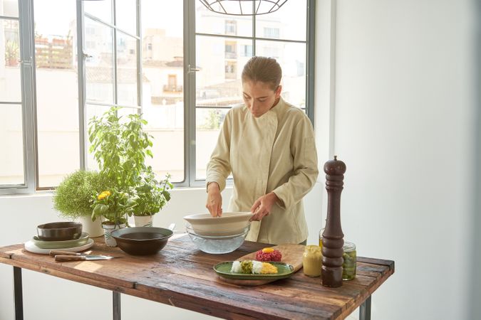 Woman preparing steak tartare at table in kitchen