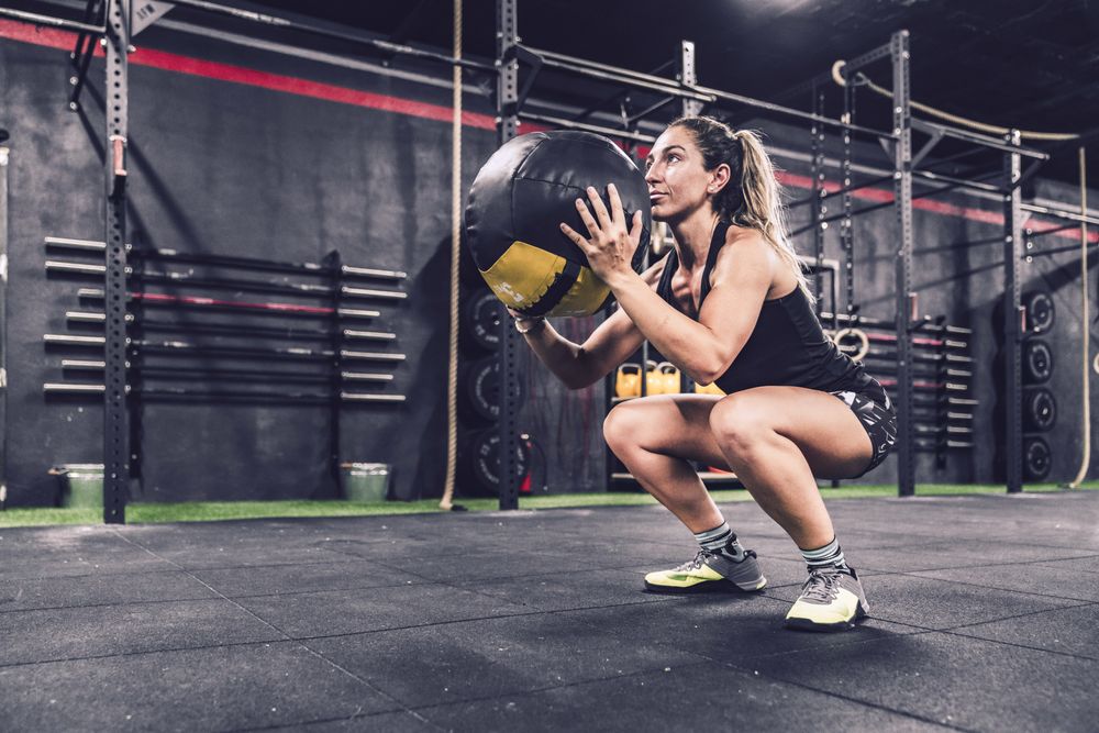 Muscular woman exercising with ball in gym