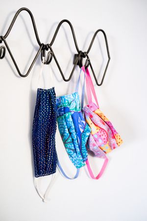 Patterned bright colors on PPE masks hanging on coat rack at home