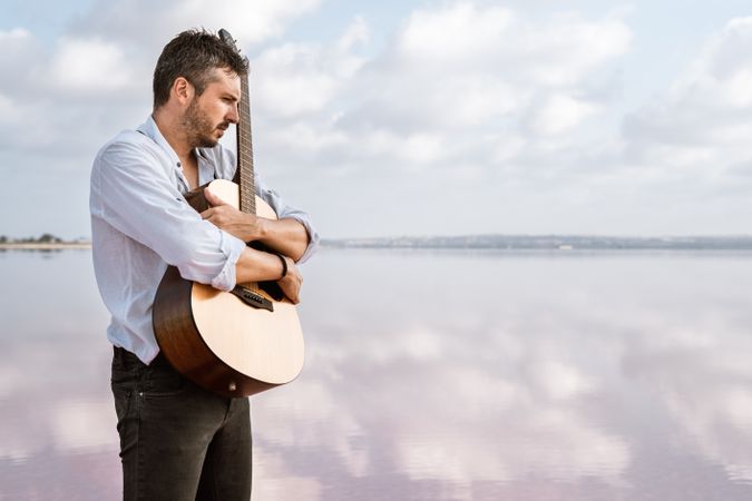 Inspired musician embracing guitar at seaside