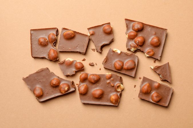 Chocolate pieces on beige background, top view. Sweet food