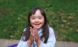 Happy little girl playing outdoors with grass in background