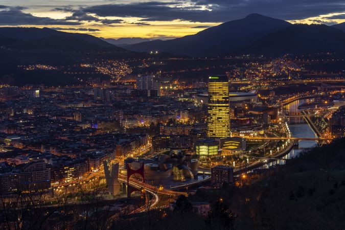 BILBAO, SPAIN - JANUARY 23, 2019: Night cityscape with mountains on background