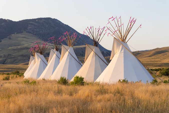 Montana, United States - August 17, 2022: Line of teepee in front of Rocky Mountains at sunset
