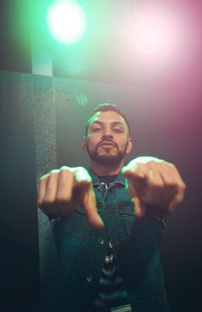 Man dancing in spotlight outstretching hand forward