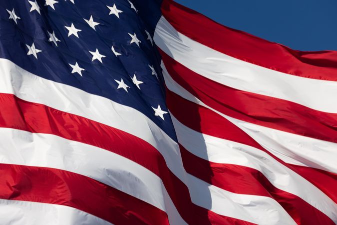 American Flag Waving In Wind Against a Deep Blue Sky.