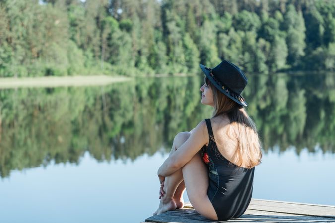Young female sitting on pier on nature