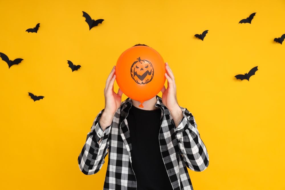 Concept of Halloween, Guy with Halloween balloon on yellow background