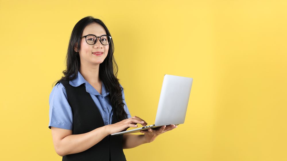 Young Asian Woman Standing and Holding Laptop