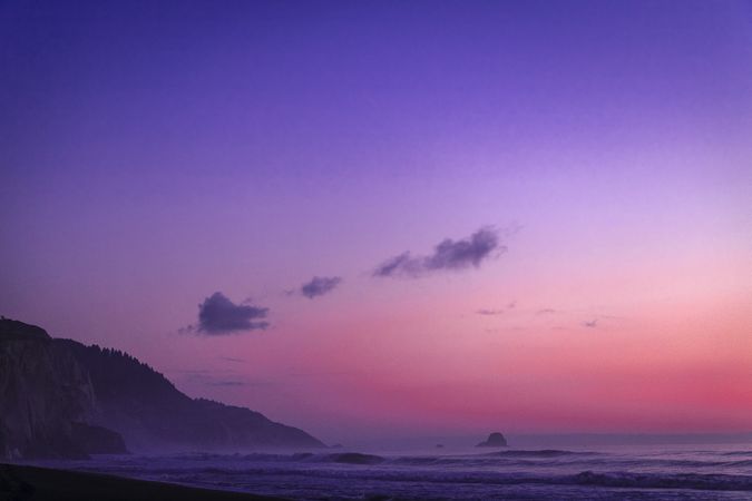 Cliffs over ocean during pink purple gradient sunset