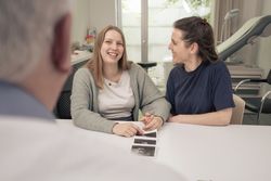 Happy couple receiving good news from their doctor at the clinic.