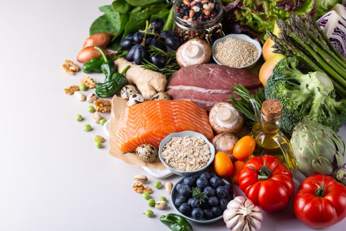 Flat lay of fresh vegetables, fruit and fish with copy space on left of image