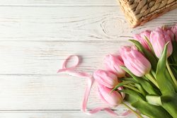 Pink tulips on wooden background, top view