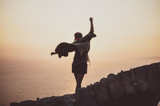 Woman with arms outstretched on castle wall overlooking sea, close up