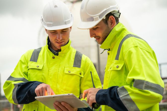 Engineer worker watching work monitor on digital tablet and talking to colleague