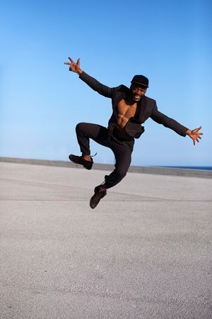 Front view of man standing outdoors with arms raised on sunny day, vertical composition