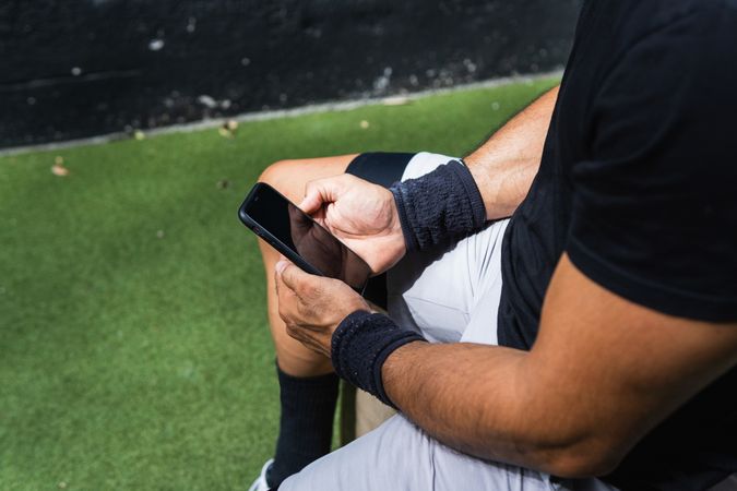 Anonymous fit man browsing smartphone during training