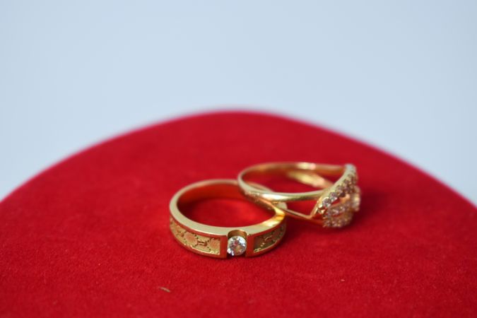 Diamond gold wedding rings on red clothed table with copy space