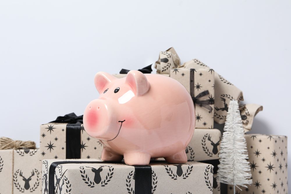 Piggy bank on gift boxes on light background, close up