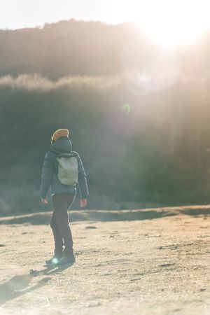 Traveler with backpack walking on autumn field