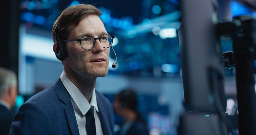 Adult Man Wearing Glasses and Headphones, Researching Investment Possibilities for International Business Corporations