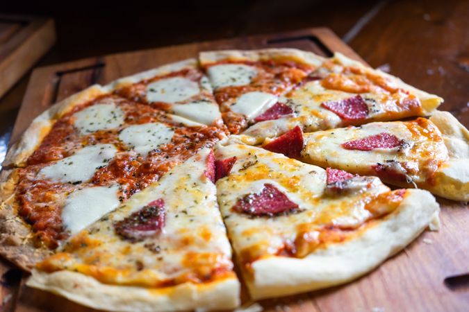 Freshly baked half and half Italian pizza on wooden board