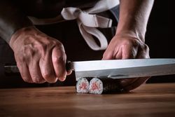Male shushi man hands preparing different pieces of makis