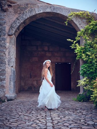 Pretty young girl in wedding dress standing at ancient building