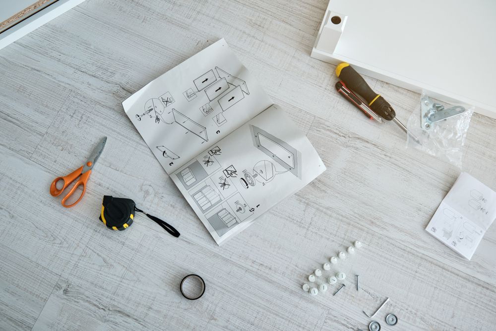 Furniture assembly instructions and various tools on wooden floo