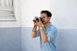 Man photographer taking photos with digital camera and looking serious