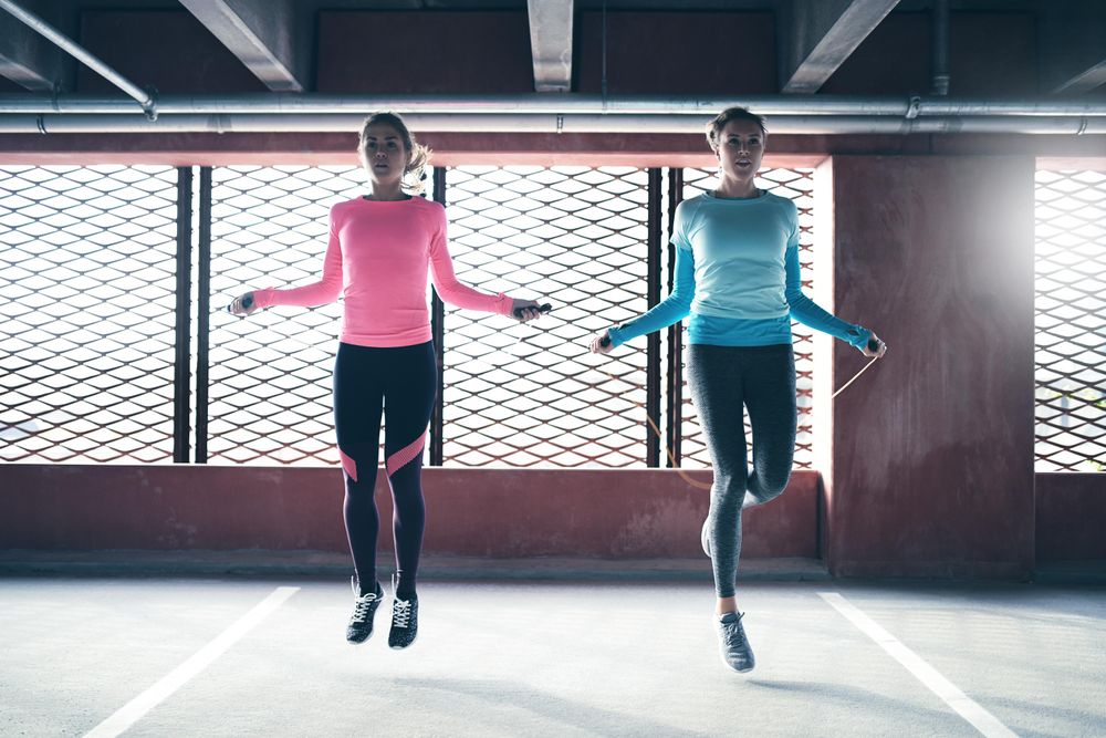 Two woman skipping rope in front of window