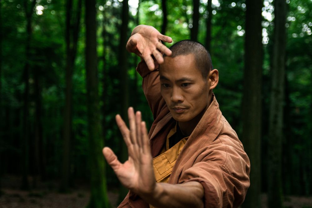 Asian man practicing martial arts in forest
