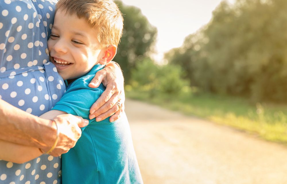 Smiling grandson hugging woman outdoors