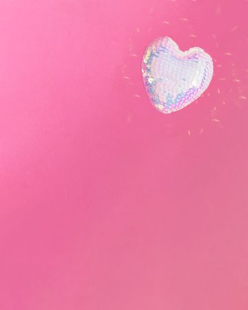 Single iridescent sequins heart on pink background