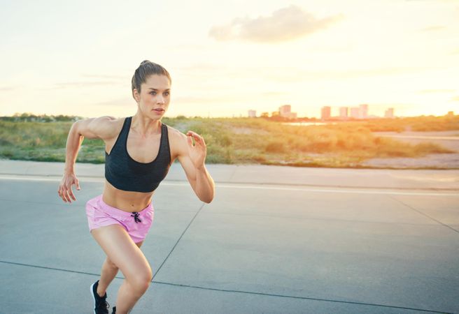 Athletic woman sprinting outside in morning light
