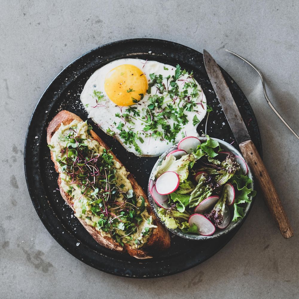 Avocado toast on sourdough bread with herbs and sprouts, square crop