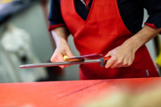 Close up of butcher in apron sharpening knife