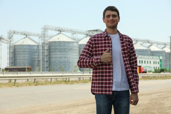 Young man against grain silos. Agriculture business