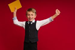 Cheerful schoolboy against red paper wall