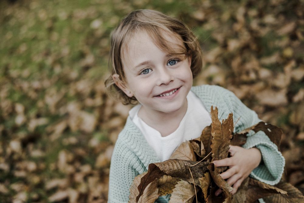 Girl with dry leaves between meadow in forest